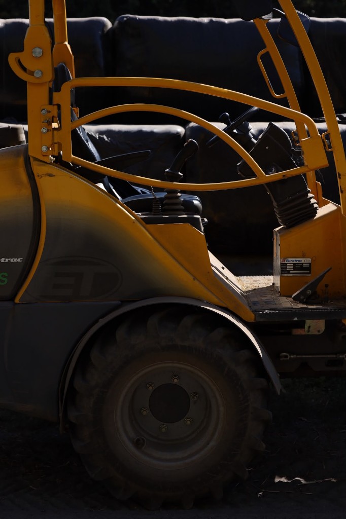 Een gele tractor of shovel voor manegebeheer, close-up van de cabine en het wiel
